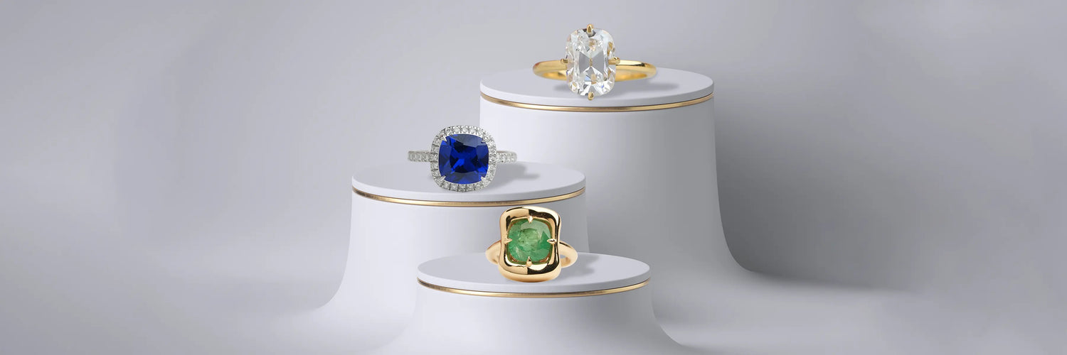 Cushion cut lab-grown diamond engagement rings in white gold — large cushion solitaire with pavé band, elongated cushion solitaire with thin pavé band, and cushion cut diamond halo with pavé band on beige pedestals