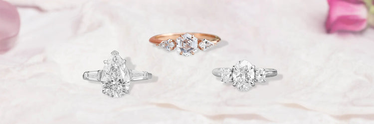 A three-stone engagement ring with a silver metal band, featuring lab-grown colored diamonds. The center stone is vibrant, flanked by two smaller diamonds.